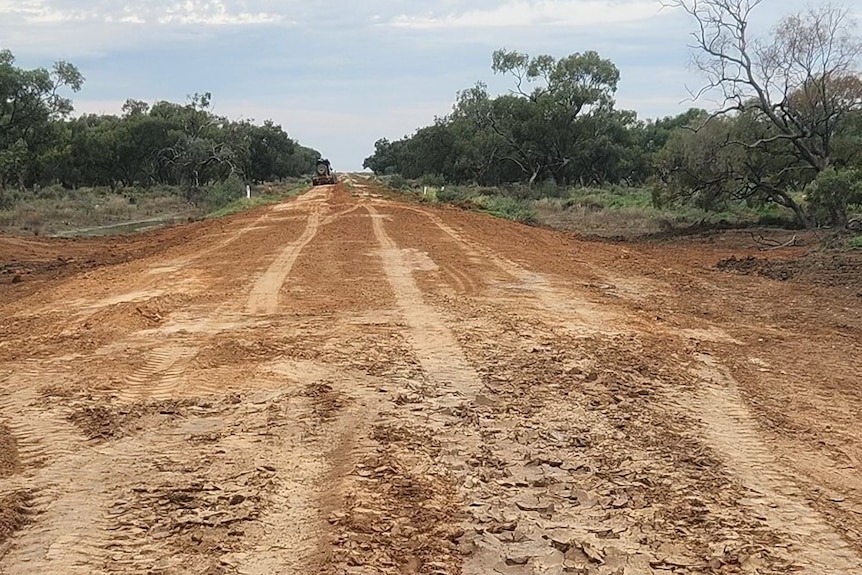 A dirt road in regional NSW, with a large digger in the background. 