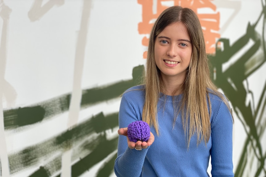 A young woman holding a purple model brain