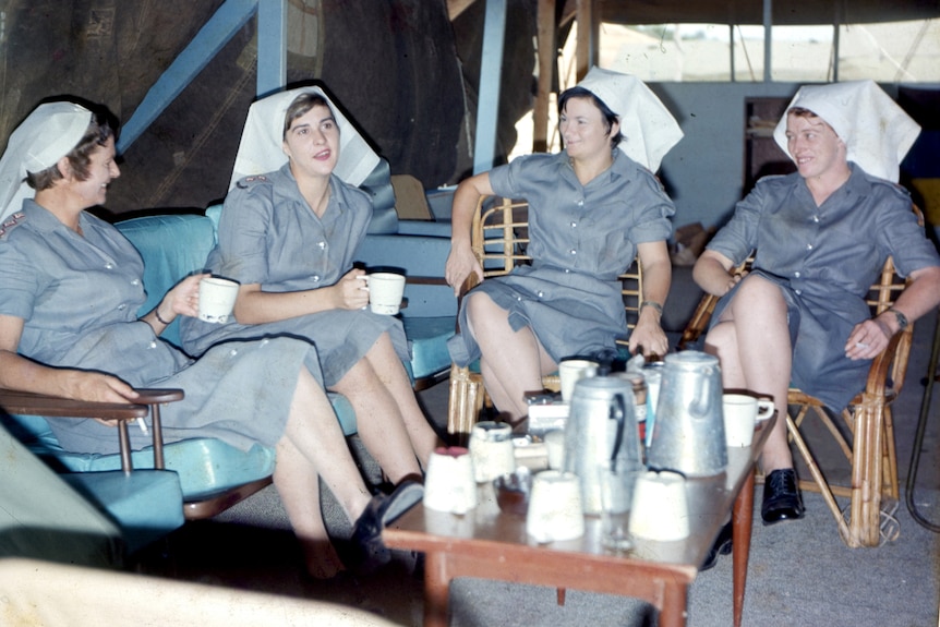 A photo from the Vietnam War showing four young women in nurses' uniform sitting around a coffee table
