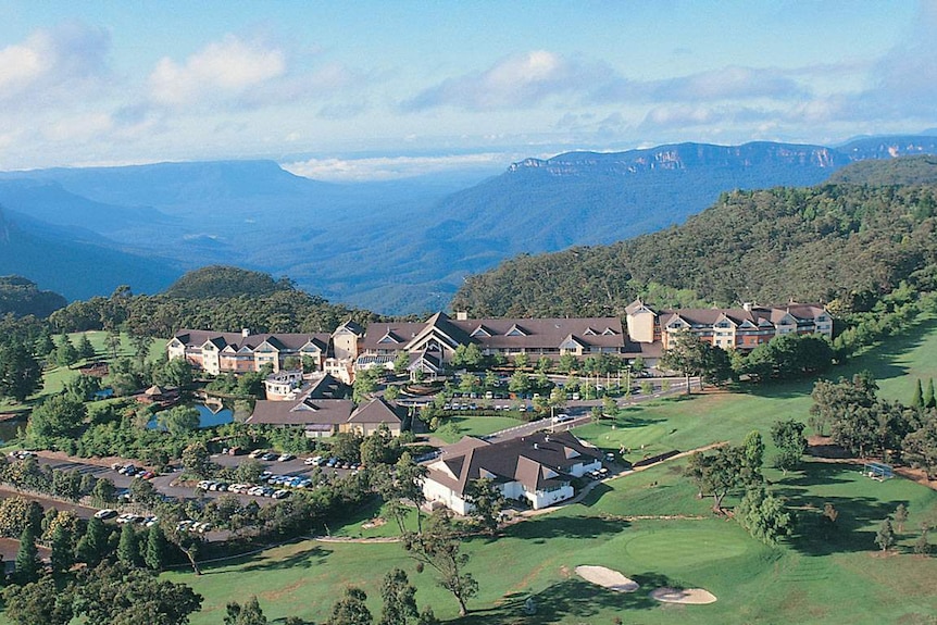 A resort surrounded by trees and green grass, with mountains in background