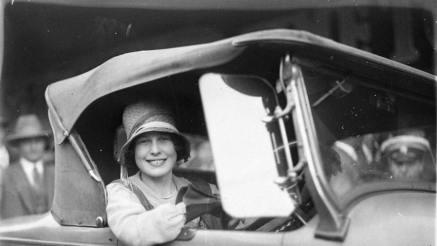 Black and white picture of Beryl Mills smiling, inside a car she won.