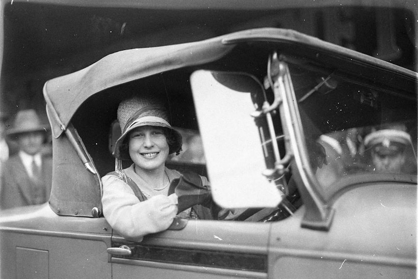 Black and white picture of Beryl Mills smiling, inside a car she won.