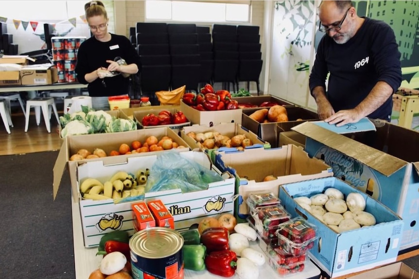 Boxes of fruit and vegetables on a table being sorted.
