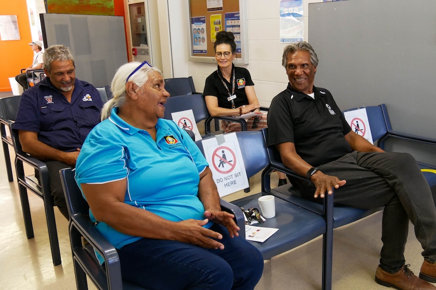 Two women and two men sit one chair apart from each other after they received their COVID-19 vaccination.