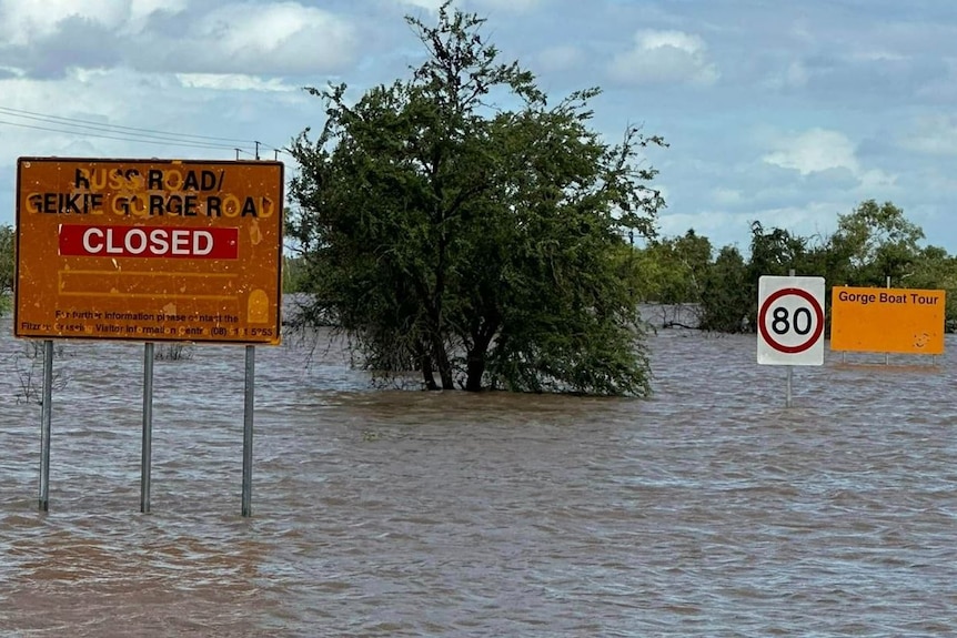 Flood waters almost covering road signs in WA's north.