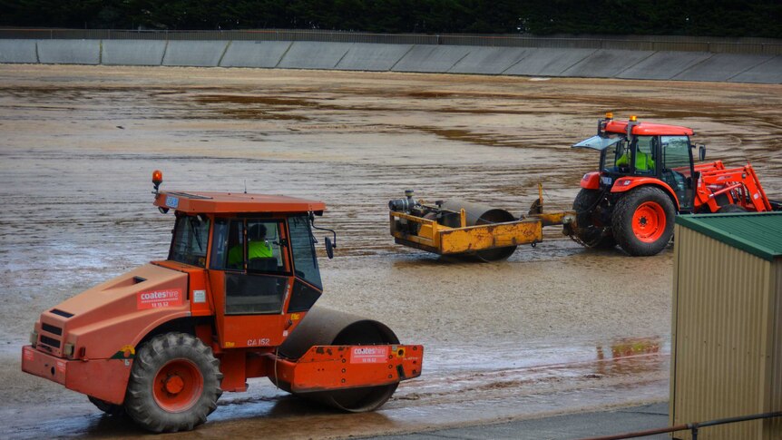 Rolling machines working on a gravel oval.