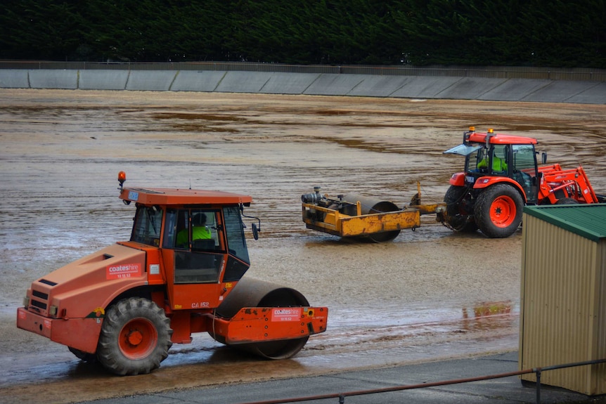 Rolling machines working on a gravel oval.