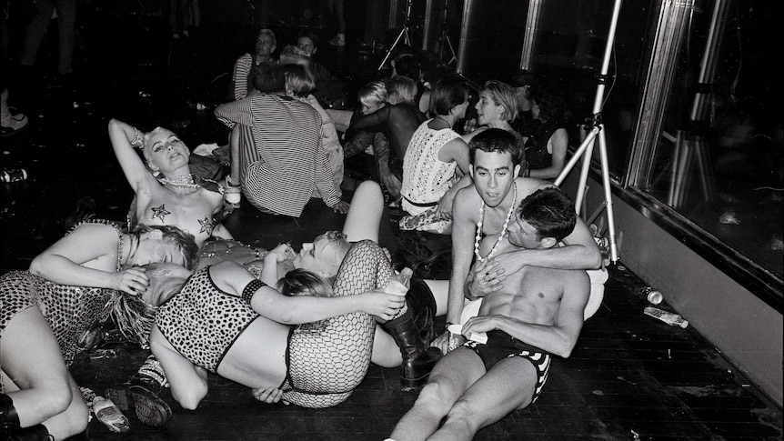 A black and white photo of a bunch of young queer people at a party in the early 90s