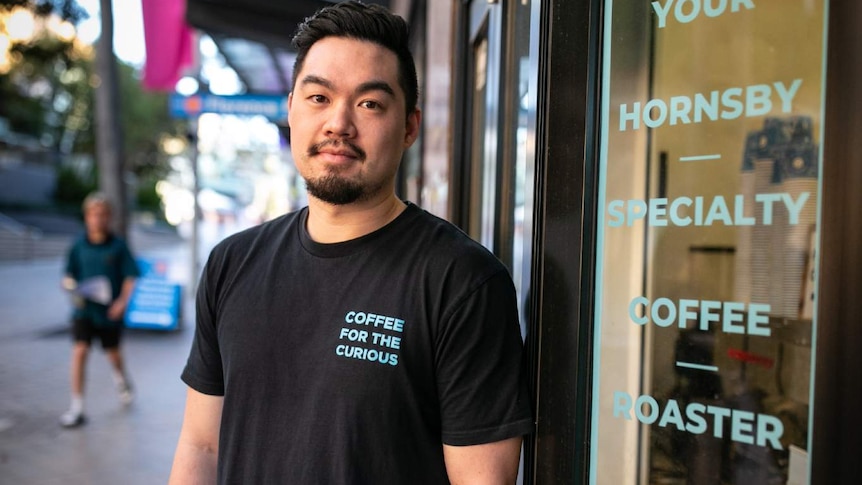 A man stands in front of a cafe