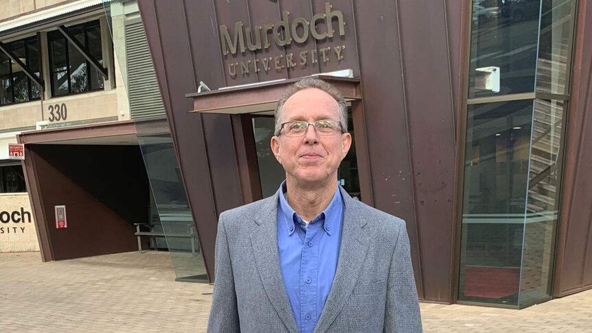 Dr Ian Cook standing outside in front of a Murdoch University building.