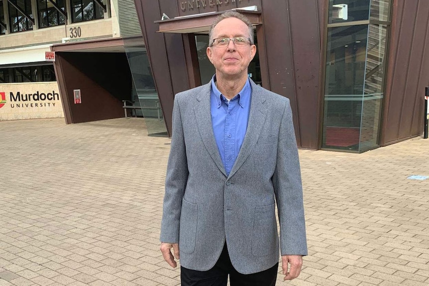 Dr Ian Cook standing outside in front of a Murdoch University building.