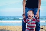 A man walks with his child on the beach