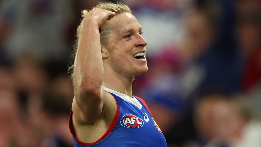 AFL player Cody Weightman celebrates, holding his hand to his head, after kicking a goal.