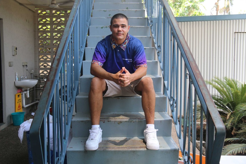 Alex Godfrey sits on an outdoor staircase and looks at the camera.