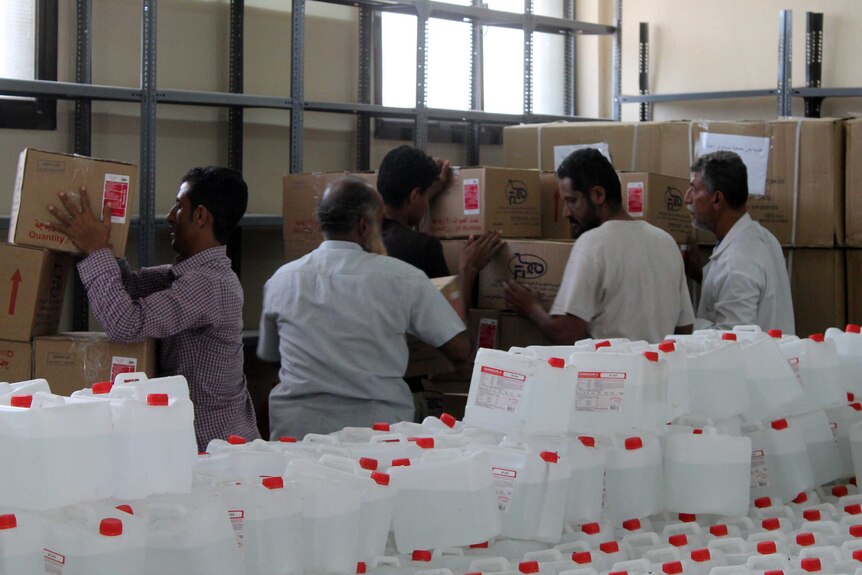 Yemenis unload boxes of aid in the city of Aden