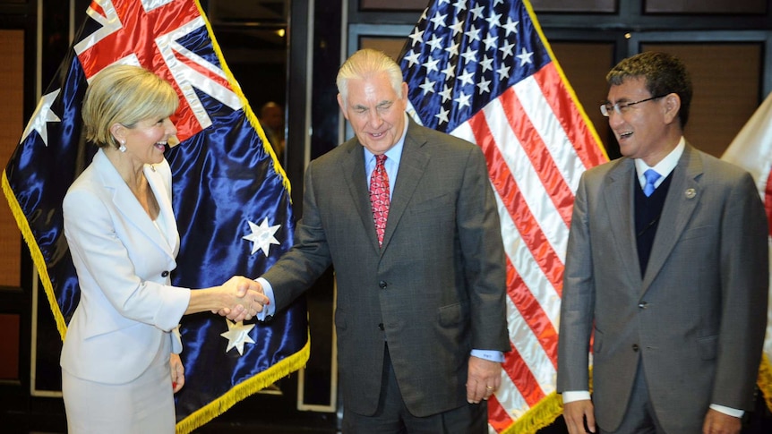 Julie Bishop shakes hands with US Secretary of State Rex Tillerson and Japan's Foreign Minister Taro Kono. They are all smiling.