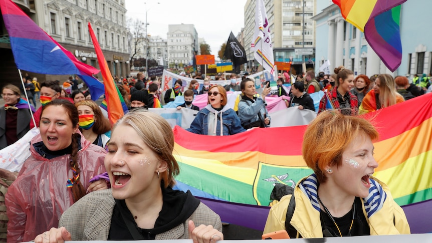 People take part in a pride march in Kyiv holding rainbow flags and chanting. 