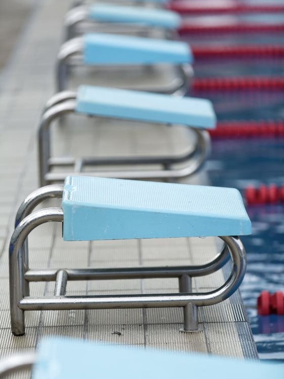 Close-up of blue diving blocks at the end of a pool.