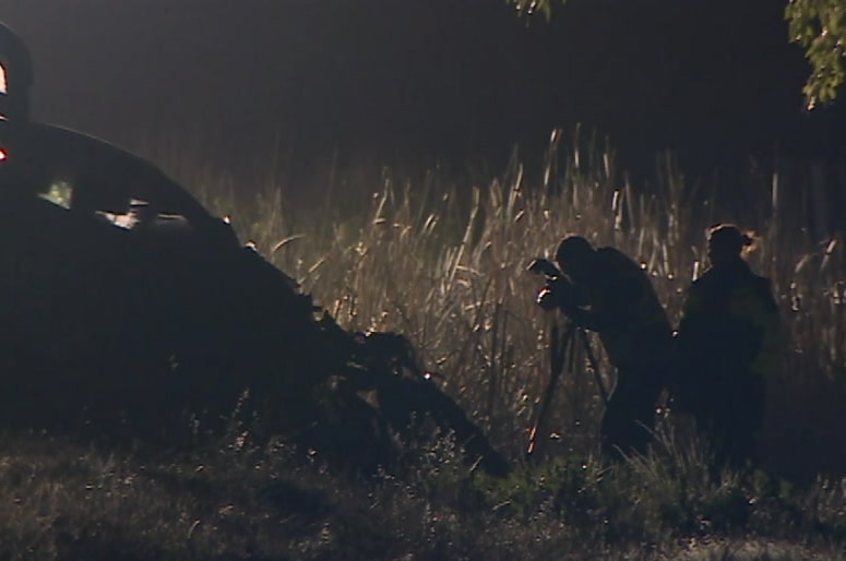 A police officer photographs the wreckage of a car at the scene of the crash.