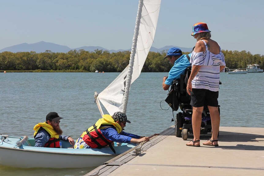 Peter Gurr assists a yacht launch from his wheelchair up on the jetty on Townsville's Ross Creek