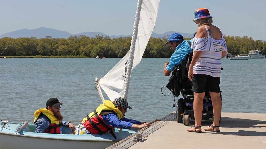 Peter Gurr assists a yacht launch from his wheelchair up on the jetty on Townsville's Ross Creek