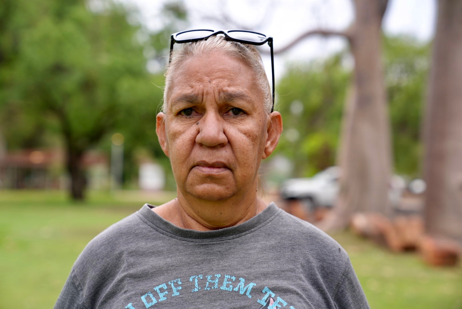 An elderly Indigenous woman looking at the camera solemnly.