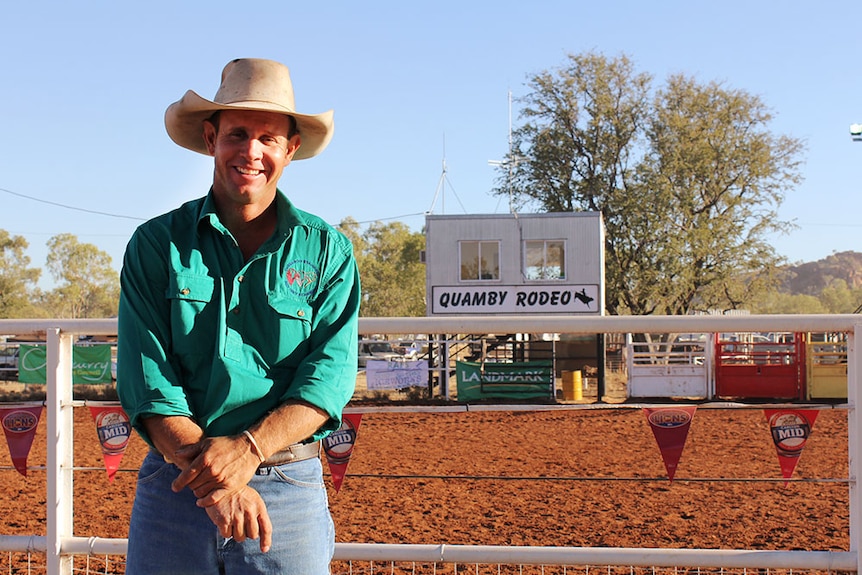 Drew Hacon smiling at the camera, standing in from of the Quamby Rodeo sign.