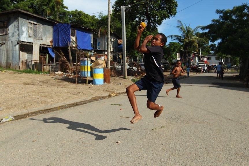 A boy bowls during a game of street cricket in Papua New Guinea.