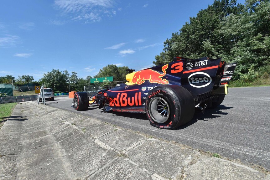 A Red Bull F1 car with a flat back left tyre is seen from the back.