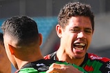 Three South Sydney NRL players embrace as they celebrate a try scored against the Newcastle Knights.