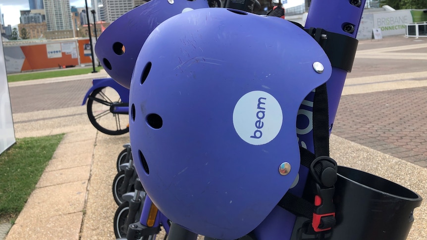 Purple e-scooters with helmets stand in a row at South Bank in Brisbane