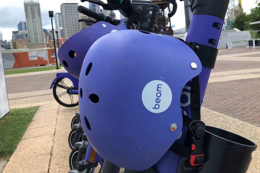 Purple e-scooters with helmets stand in a row at South Bank in Brisbane