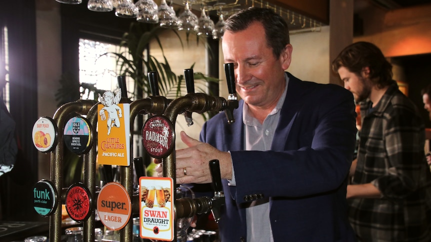 Mark McGowan standing behind a bar pouring a pint of beer 
