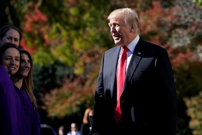 Donald trump smiles as he greets college athletes.