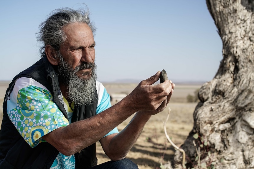 Gomeroi Traditional Custodian Steve Talbott inspects an Aboriginal artefact