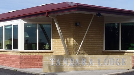 A red and yellow brig building with a silver sign reading Tandara Lodge.