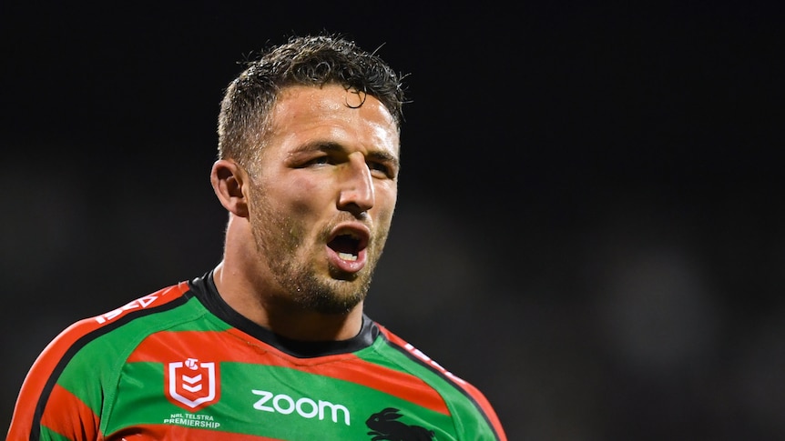 Sam Burgess opens his mouth and walks forwards whilst wearing a red and green rugby jersey.