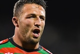 Sam Burgess opens his mouth and walks forwards whilst wearing a red and green rugby jersey.