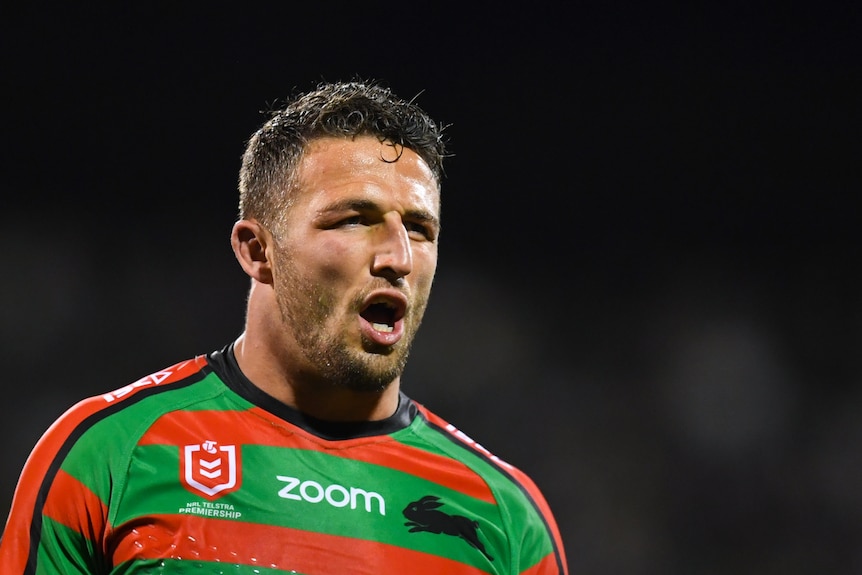 Sam Burgess opens his mouth and walks forwards whilst wearing a red and green rugby jersey.