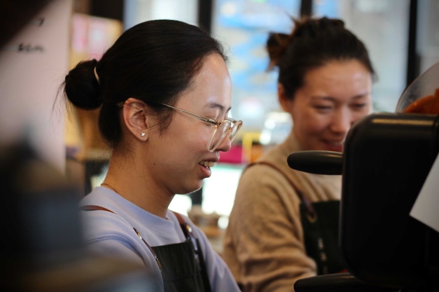 Zanine smiles while working at the coffee machine.