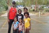 A man a his five daughters stand in a flooded river. 