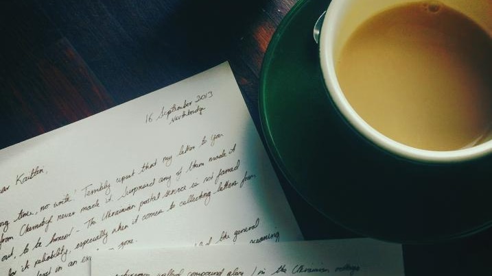 A table laid out with a letter and a cup of coffee.