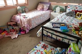 A room with two single beds with toys and books on the end of each.