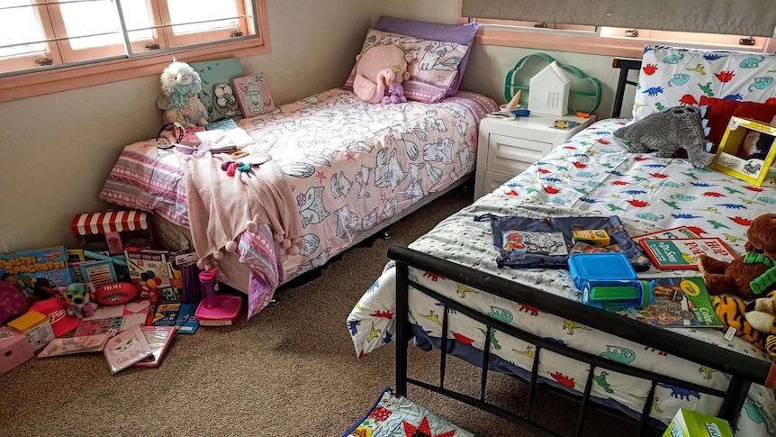 A room with two single beds with toys and books on the end of each.