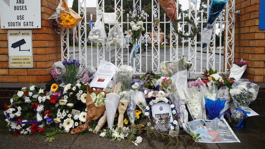Floral tributes are placed at the gate of the Police Academy for four police officers who died in the line of duty.