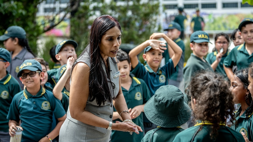 Principal Manisha Gazula surrounded by happy-looking primary school kids in the school grounds.