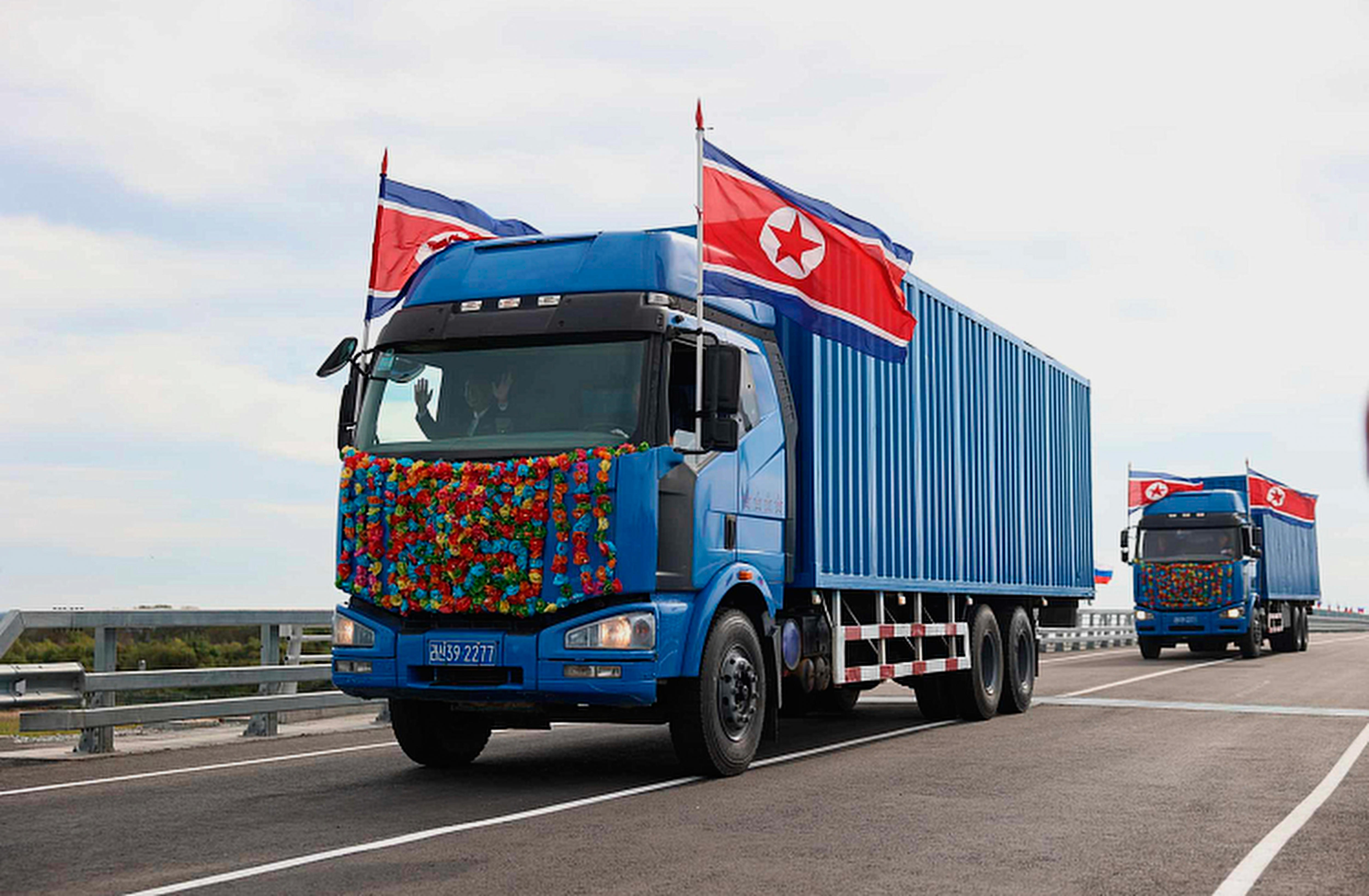 A blue truck covered in North Korean flags.