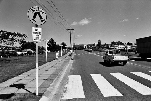 Black and white photo of a hitchhiking zone near a pedestrian stop. 