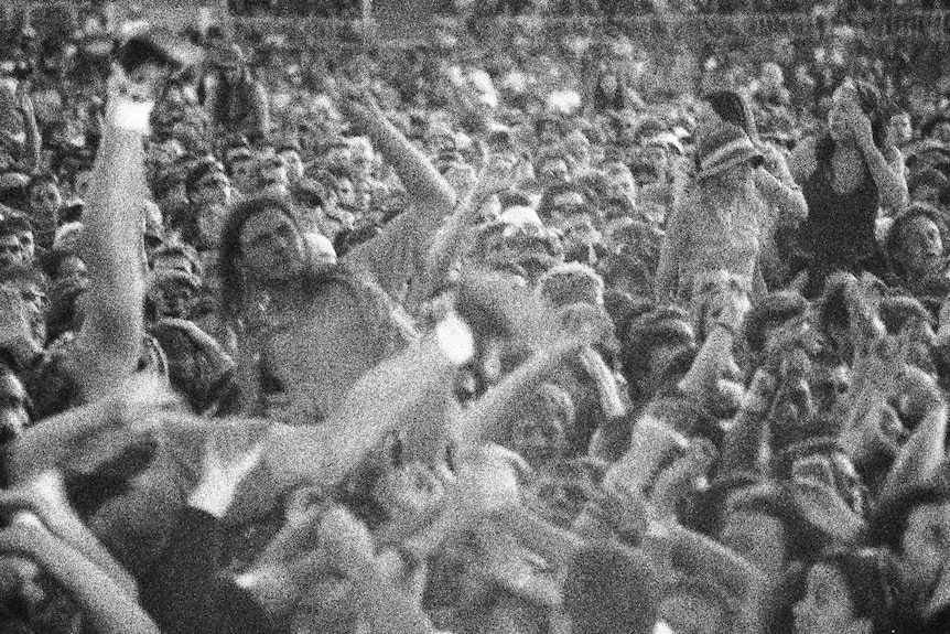 A crowd of people with hands and legs in the air
