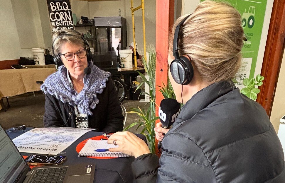 woman in woollen scarf with headphones being interviewed by lady with blonde hair seen from behind